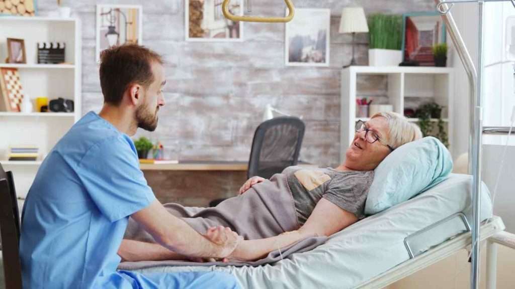 Caregiver providing bedside comfort to a senior.