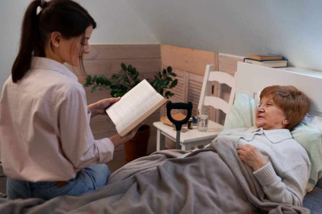 Caregiver reading to a senior in bed.