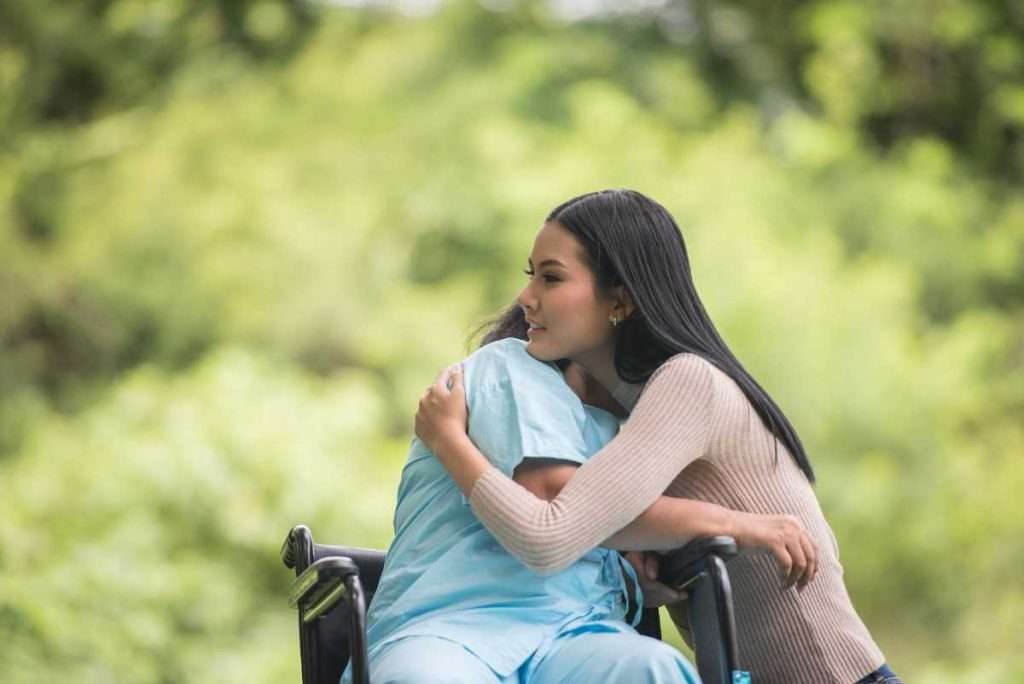 Caregiver offering emotional support to a senior in a wheelchair.