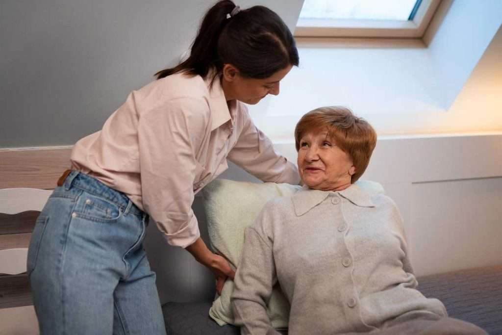 Caregiver helping a senior sit on a couch.